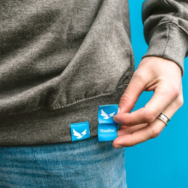 Close up of hem tag on sweatshirt and one held up next to it 